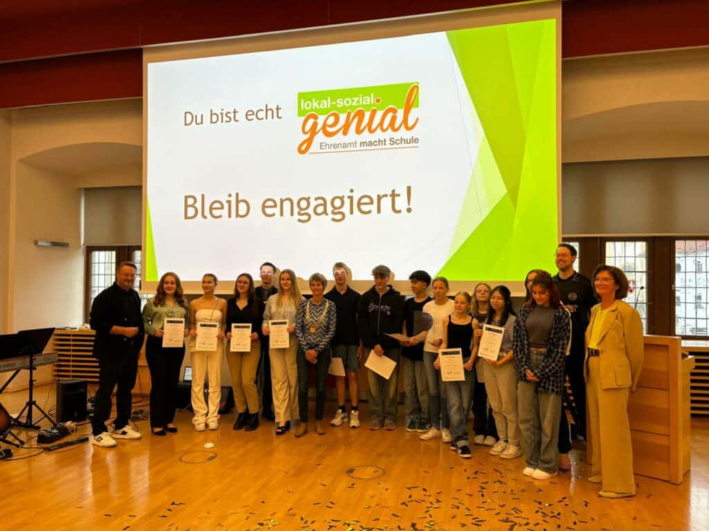 Eine Gruppe von Menschen steht vor einem großen Bildschirm.